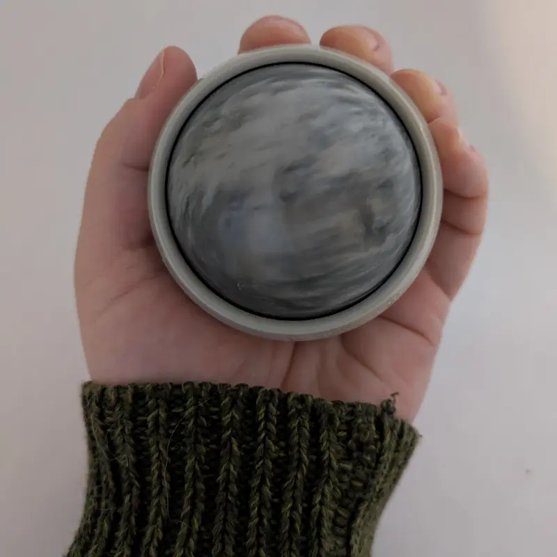 Main tenant une balle de massage manuelle de style marbre pour un soulagement musculaire ciblé.