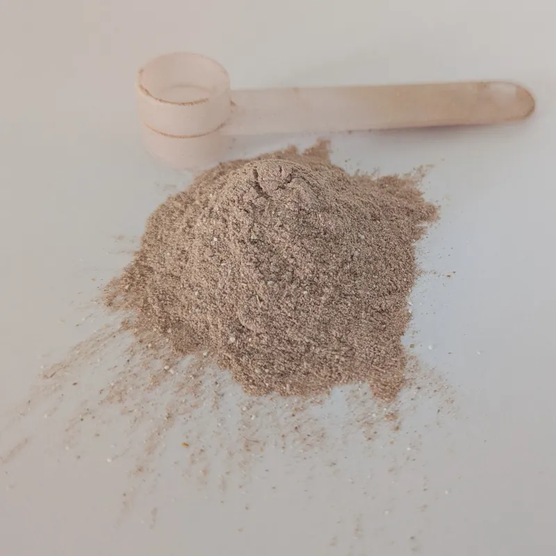 A pile of light brown bladder health powder next to a clear plastic measuring scoop.