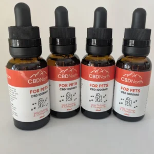 Quatre bouteilles ambrées d'huile de CBD pour animaux CBDNorth avec des étiquettes rouges et blanches.