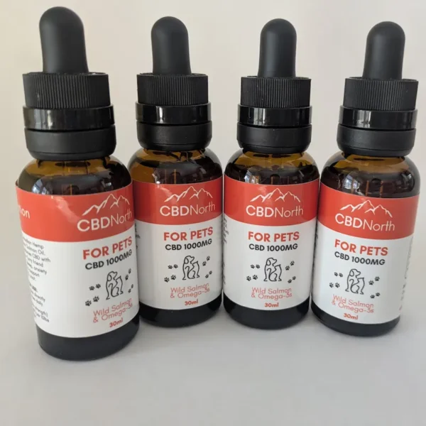 Four amber bottles of CBDNorth CBD oil for pets with red and white labels.