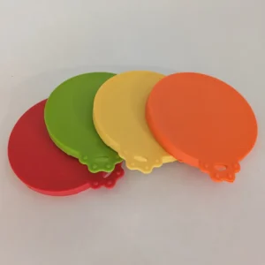 Un ensemble de quatre couvercles en silicone pour boîtes de conserve pour chiens en rouge, vert, jaune et orange.