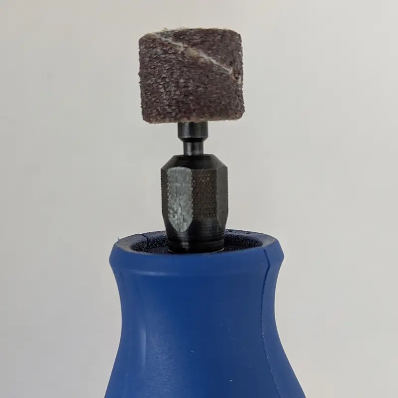 Close-up of the sanding drum attachment on a blue Dremel pet tool.