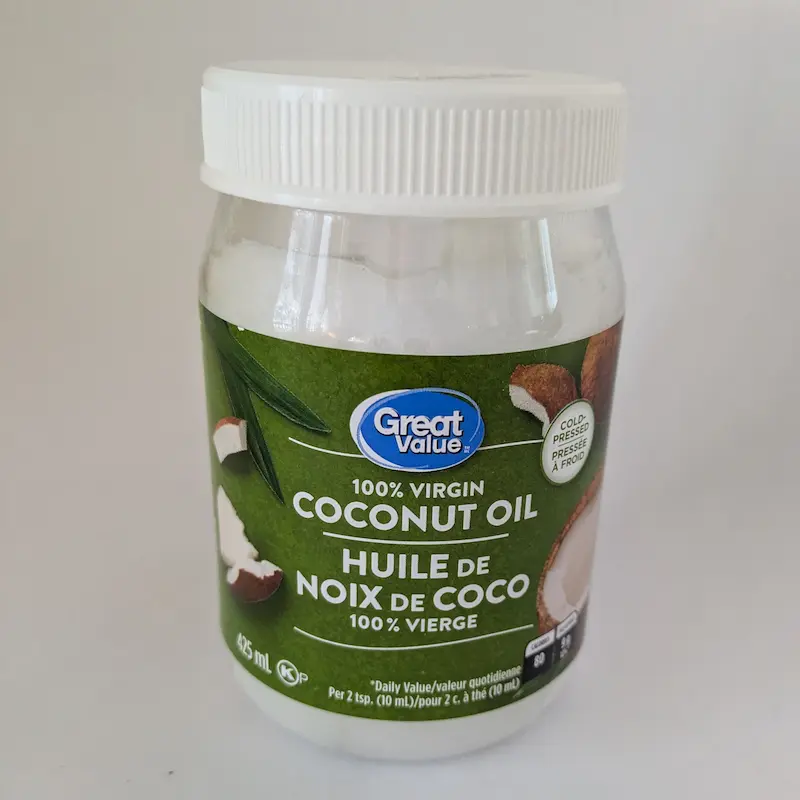 Un pot d'huile de coco 100 % vierge pour les soins topiques de la peau des chiens âgés.