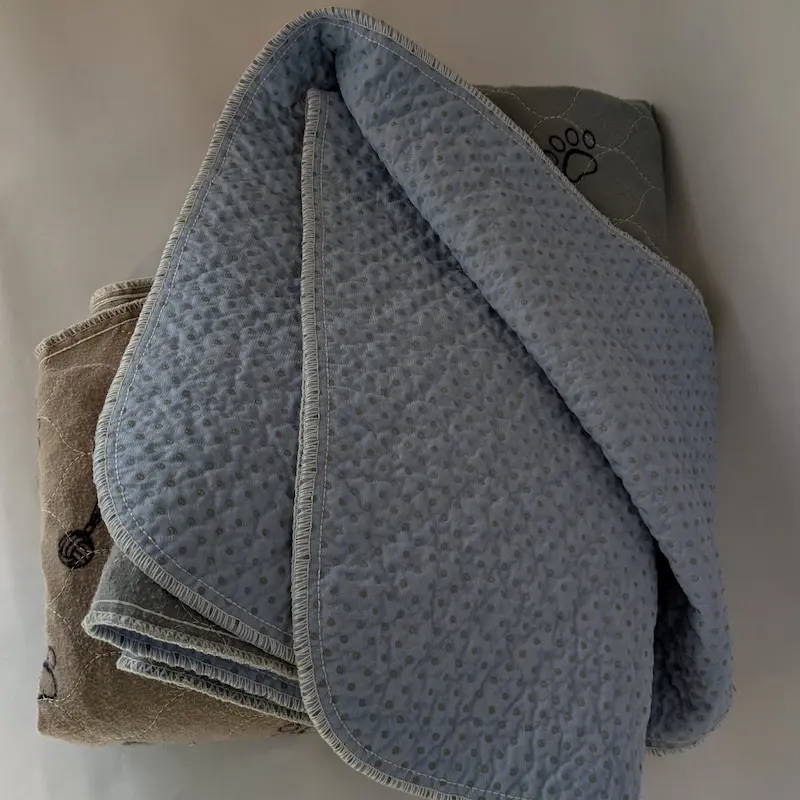 Close-up of a large quilted grey washable pad showing the absorbent texture.