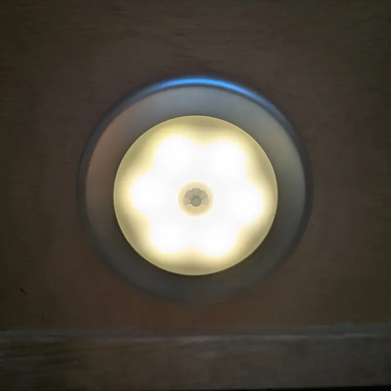 Circular LED motion sensor light designed to stick to walls for hallway safety.