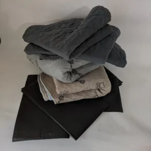 Une pile de grands et petits tapis de propreté lavables gris pour l'incontinence des chiens âgés.
