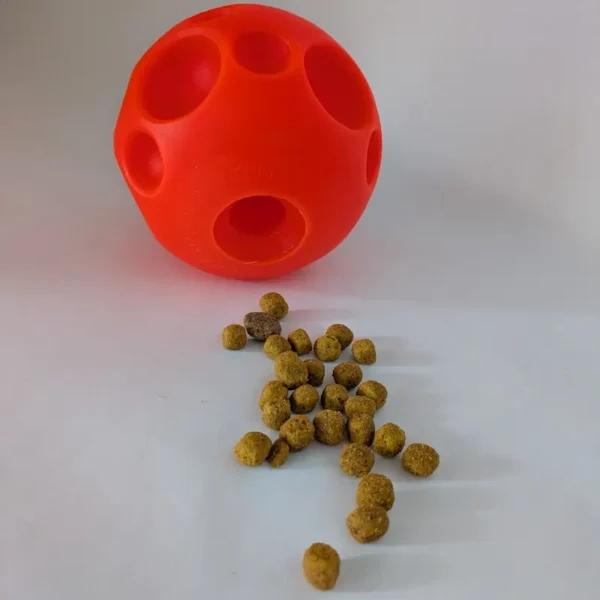Orange treat-dispensing ball with kibble on a white background.