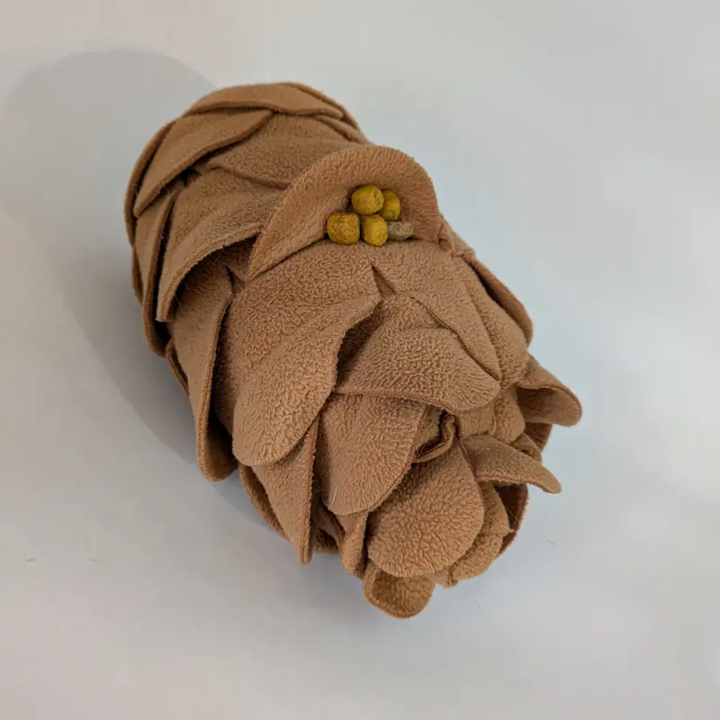 Une cocotte de pin à fouiller en polaire marron avec des friandises cachées dans les couches de tissu.