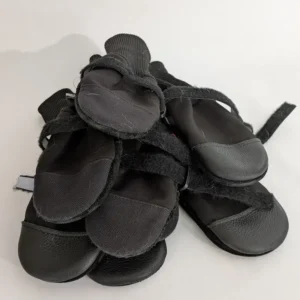 A pile of black Muttluks winter dog boots with reflective straps and durable soles.