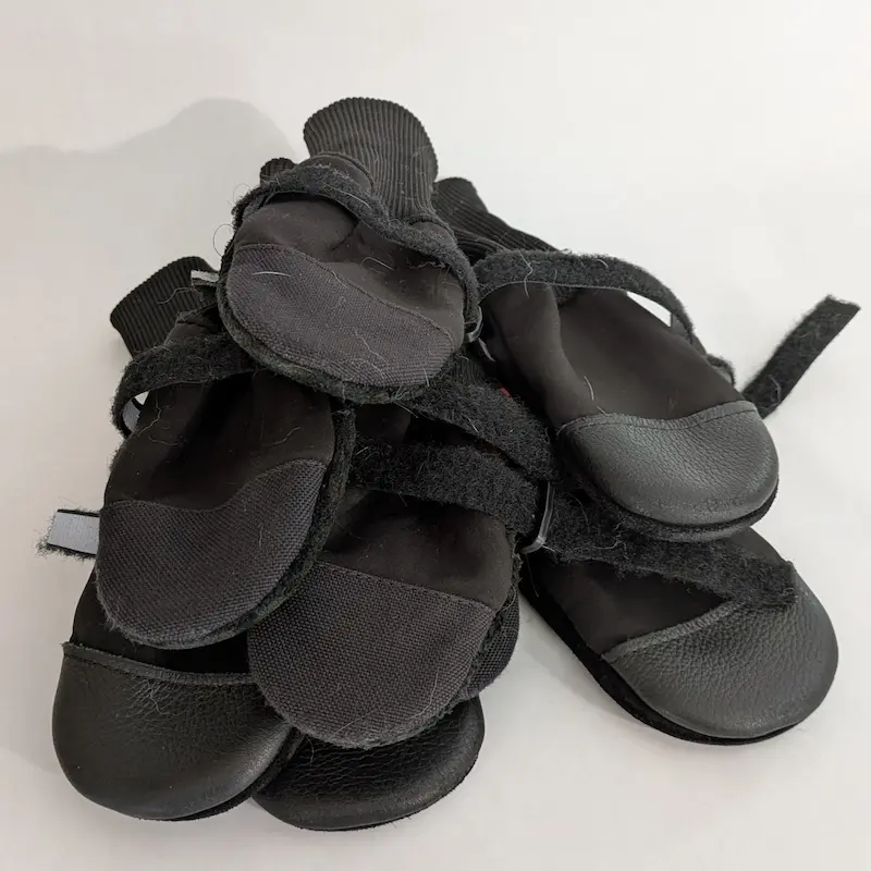 A pile of black Muttluks winter dog boots with reflective straps and durable soles.