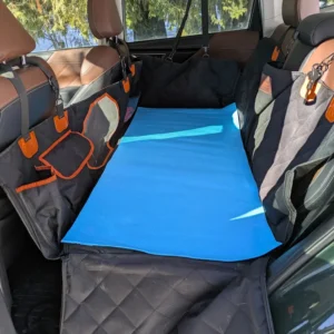 Rigid-bottom quilted car hammock for dogs installed in the back seat of a car with a blue yoga mat on the bottom for traction.
