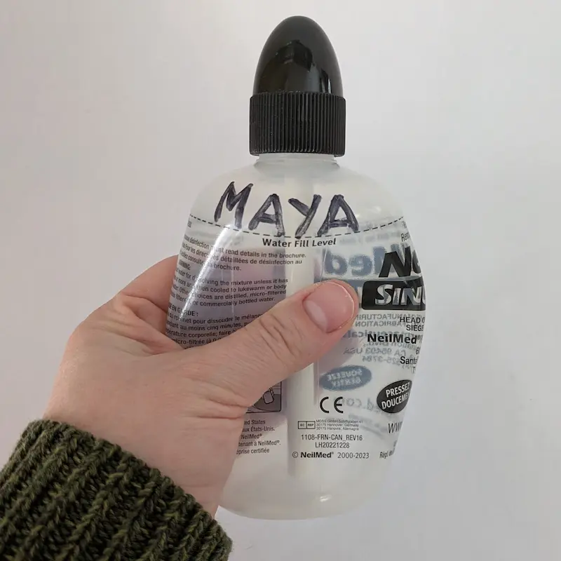 A hand squeezing the plastic rinse bottle to demonstrate the controlled flow.