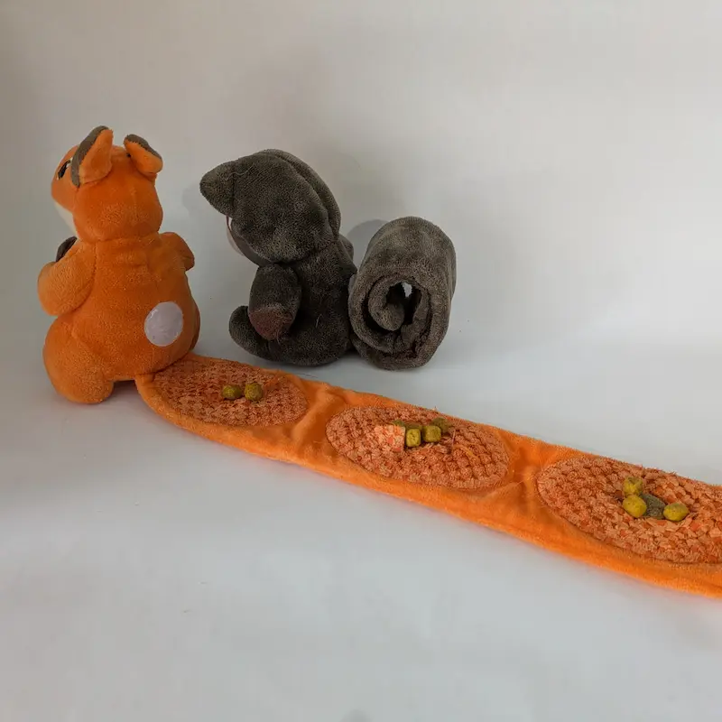 Un jouet en peluche écureuil orange attaché à un long tapis à fouiller pour la recherche de nourriture.